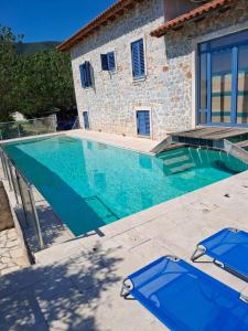 a large swimming pool with blue chairs in front of a house at villa olivedream in Nea Epidavros