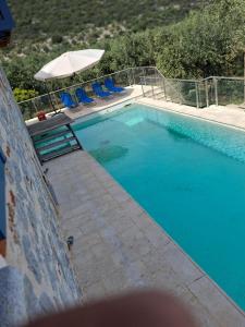 a swimming pool with blue chairs and an umbrella at villa olivedream in Nea Epidavros
