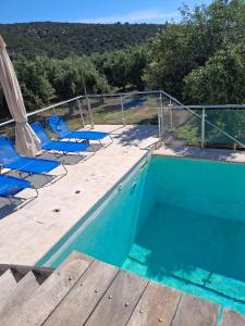 a pool with blue chairs and a deck with a view at villa olivedream in Nea Epidavros