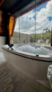 a white bath tub sitting in a room with a window at Pousada Estrela Dalva in Piracaia