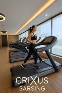 a woman running on a treadmill in a gym at Crixus Hotels Sarsing in Sarsing