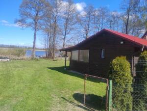 a small house with a fence in the yard at Domek nad jeziorem -Mazury- Linia Brzegowa in Piotrowice