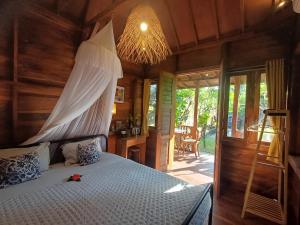 a bedroom with a bed with a canopy at Mondok Dini in Ketewel
