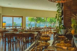 a restaurant with tables and chairs with a view of the ocean at Hotel VillaReal Charme in Guaratuba