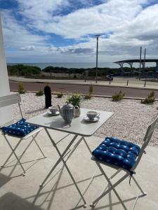 a white table and two chairs with bowls on it at Coastal Calm Seascapes Halls Head in Falcon