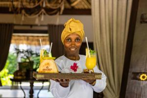 a woman holding a tray with two drinks on it at The Palms Zanzibar in Bwejuu