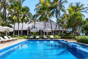 a swimming pool in front of a resort with palm trees at The Palms Zanzibar in Bwejuu
