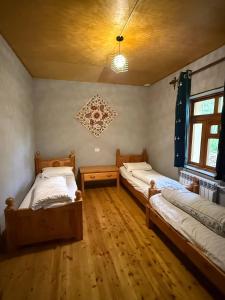 two beds in a room with wooden floors at Nurata Eco Guesthouse in Yukary-Ukhum