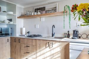 a kitchen with wooden cabinets and a sink at Sunny Cove Stays in Fish Hoek
