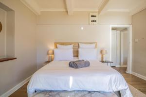 a bedroom with a large white bed with two lamps at Sunny Cove Stays in Fish Hoek