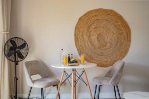 a room with a table and two chairs and a fan at Sunny Cove Stays in Fish Hoek +24 photos