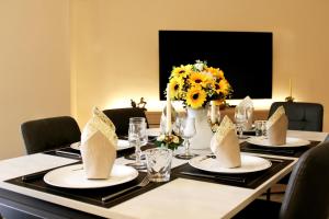 a table with plates and a vase of sunflowers at L' Antico Scoglio Appartamenti comfort Nocera Terinese Scalo - Fino a 11 Ospiti - Piscina - Navetta Aeroporto-Stazione & Multi-Destinazioni - Spiaggia a 300mt - Giardino e Zona pranzo all'aperto - WiFi & SmartTV - Aria Condizionata in Nocera Terinese
