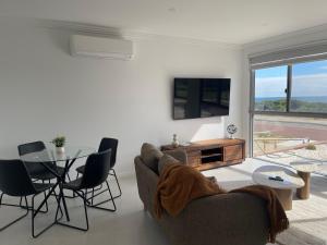 a living room with a couch and a table and a tv at Coastal Calm Seascapes Halls Head in Falcon
