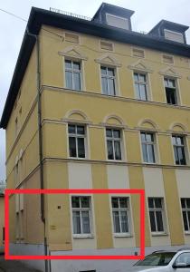 ein gelbes Gebäude mit einem roten Pfeil davor in der Unterkunft MonAppart in Gera