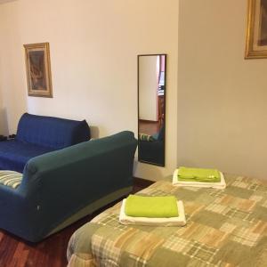 Zimmer mit 2 Betten, einem blauen Sofa und einem Spiegel in der Unterkunft Ampio monolocale in Brescia