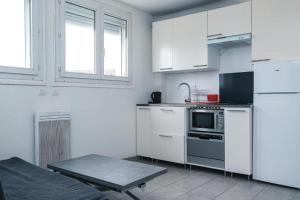 a kitchen with white cabinets and a stove at Le KA NOE in Vaires-sur-Marne