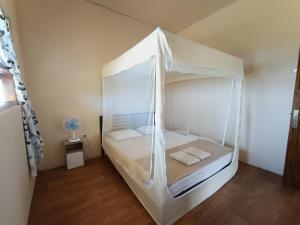 a small bedroom with a white canopy bed at Purangjompa Homestay in Tiwuronto