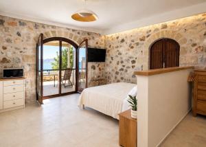 a bedroom with a bed and a tv and a balcony at Papanestoras Apartments in Kardamyli