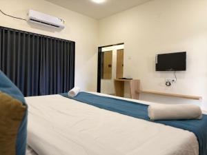 a bedroom with a bed and a flat screen tv at Sylvara Resort in Sasan Gir