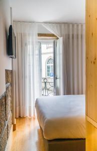 a bedroom with a bed and a tv and a window at Ribeiredge Guest House in Porto