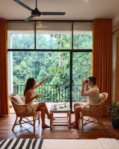 a man and woman sitting in chairs in front of a window at Ella Green Cottages in Ella