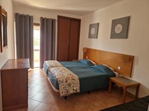 a bedroom with a bed and a table and a window at Castelos da Rocha in Portimão