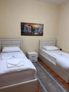 a bedroom with two beds and a painting on the wall at Vila Beliz in Tirana