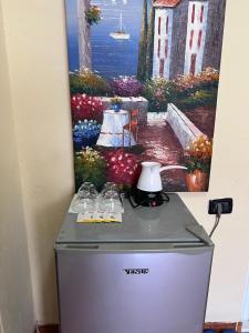 a refrigerator with glasses on it in front of a painting at Vila Beliz in Tirana