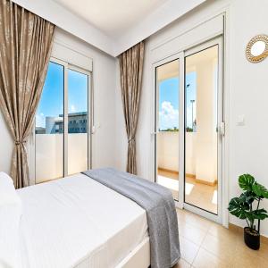 a bedroom with a bed and large windows at Gennadi Villa Mare 300m from the Beach in Gennadi