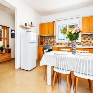 a kitchen with a white refrigerator and a table with chairs at Gennadi Villa Mare 300m from the Beach in Gennadi