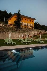 a building with chairs and a pool in front of it at Chalet Bellavista in Spiazzi Di Caprino