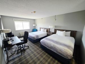 a hotel room with two beds and a desk at AmericInn by Wyndham Minot in Minot