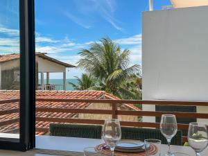 a table with two wine glasses on a balcony at Chalé by Vila Manga Rosa in Pipa