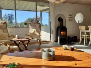 a living room with a fireplace and a table at Sommerhuset i Saltum in Saltum