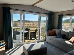 a living room with a couch and a table with a balcony at Barnharrow Holiday Park in Newton Stewart