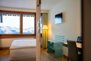 a bedroom with a bed and a desk and a window at Wellness Hotel Stoos in Stoos