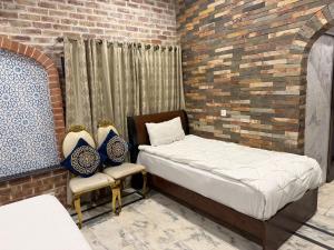 a bedroom with two beds and a chair in it at Hayatt Palace Sukkur in Sukkur