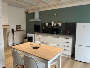 a kitchen with a table with chairs and a refrigerator at Maison de Village in Leuglay