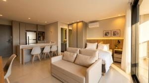 a bedroom with a bed and a couch and a kitchen at Facilidade no Coração da Cidade in Campo Grande