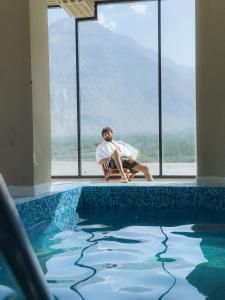 a man sitting next to a swimming pool at FortuNorth in Skardu