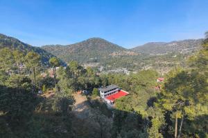 a house on a hill with mountains in the background at Aranya Tara in Bhīm Tāl