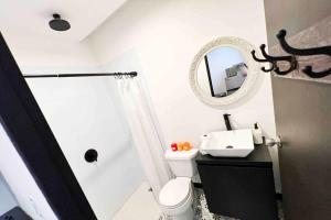 a bathroom with a toilet and a sink and a mirror at 5.4 Loft • Lobby • Generator • Parking • 2nd Floor in Mayaguez