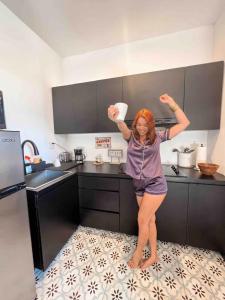 a woman standing in a kitchen with her arms in the air at 5.6 Loft • Lobby • Generator • Parking • 2nd Floor in Mayaguez
