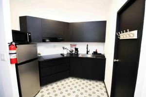 a kitchen with black cabinets and a sink and a refrigerator at 5.2 Loft • Lobby • Generator • Parking • 2nd Floor in Mayaguez