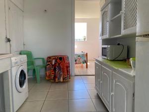 a kitchen with a washing machine and a microwave at Bel appartement à Damencourt in Le Moule