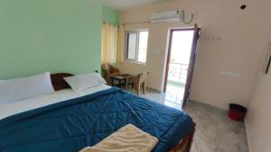 a bedroom with a bed and a table and a window at Ronazio Beach View Residency in Auroville