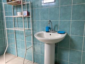 a bathroom with a white sink and blue tiles at Bel appartement à Damencourt in Le Moule