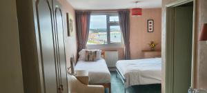 a small room with two beds and a window at The Sands Hotel in Paignton