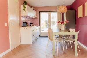 a kitchen with pink walls and a table and chairs at Vakantiehuis dicht bij het strand in Ouddorp