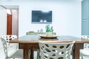 a dining room with a wooden table and white chairs at Cerenea House BiancAntò in Isola del Liri